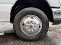 Close-up of the wheel and tire of a 2013 Ford Econoline showing a shiny chrome hubcap and tread pattern on the tire