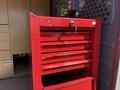 A red tool chest with multiple drawers and a key in the lock