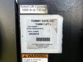 A label on a 2014 Mitsubishi Fuso FE truck featuring the Tommy Gate Co logo part number and warning information