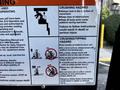 A safety instruction sign detailing crushing and tipping hazards associated with operating a 2000 JLG 12SP lift with illustrations and warnings