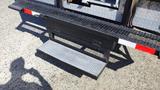 A metal step platform with a textured surface extending from a 2009 GMC W5500-HD truck designed for easier access