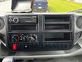 Dashboard of a 2019 Hino 195 with controls for air conditioning and audio system along with multiple storage compartments