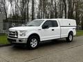 A white 2017 Ford F-150 with a high box cover mounted in the truck bed and four wheel drive capability