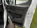 A close-up view of the driver side door panel of a 2021 Ford Transit featuring a gray interior with controls and a handle