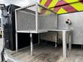 A 2007 Ford F-550 with a metallic mesh storage unit and a small metal table on the truck bed designed for utility purposes