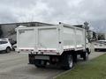 A white 2014 Hino 195 truck with a flatbed and a closed cargo area is parked on a street