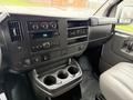 Interior view of a 2014 GMC Savana dashboard featuring a radio, climate controls, and a console with cup holders