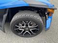 A blue 2020 Polaris Slingshot with a focus on its front tire featuring a black alloy rim and a textured tread pattern