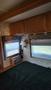 Interior view of a 2007 Winnebago Adventure with wooden cabinetry a lamp and a small radio near a window with blinds