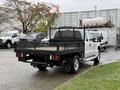 A white 2016 Ford F-350 SD with a black flatbed is parked, featuring a mesh sides and rear, showing its utility design and rugged appearance