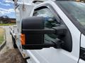 A close-up of the side mirror of a white 2015 Ford F-350 SD showing the mirror and an orange light indicator