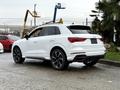 A 2024 Audi Q3 in white with sleek lines and a sporty design featuring black accents and alloy wheels viewed from the rear