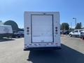 A white 2012 Ford Econoline van viewed from the rear with a closed roll-up door and red taillights