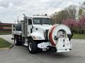 A 2016 Peterbilt 348 truck with a large cylindrical tank and a hose reel attached to the front features a white exterior and multiple orange lights on the roof