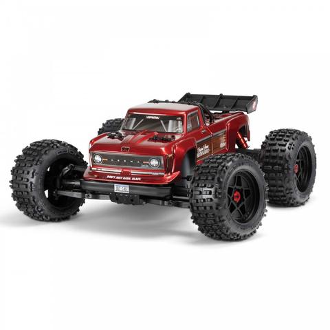 A red Arrma 1/10 OUTCAST 4S 4X4 RTR Brushless Stunt Truck with oversized black tires and a rugged body designed for off-road performance