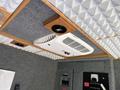 A 2011 Ford F-650 interior with a mounted air conditioning unit and speakers on the ceiling along with control panels and a textured gray surface