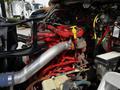 The engine of a 2012 Freightliner M2 106 with red components and various hoses and wires visible