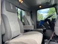 Interior of a 2013 Kenworth T370 featuring two gray fabric seats with a dotted pattern and a driver's console displaying controls and an electronic device holder