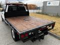 A 2020 Ford F-350 with a flatbed featuring wooden planks and a metal access panel on the surface