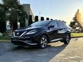 A 2021 Nissan Murano in black with a sleek design featuring a distinctive grille and chrome accents parked on a pavement with sunlight highlighting its contours