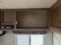 An empty overhead cabinet in a 2018 Westland Travelaire with a small audio system partially visible and no items placed inside