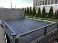 A 2018 Ford F-450 SD truck with a flatbed featuring a black wooden surface and a metal mesh railing along the sides