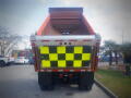 A 2016 International WorkStar 7500 dump truck with an orange bed and a checkerboard-patterned rear panel in bright yellow and black
