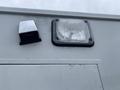 Close-up of two lights on the side of a 2014 Chevrolet Express one is a square light with a clear lens and the other is a rectangular light with a rugged surface