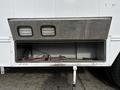 A 2006 GMC C5000 with a metallic storage compartment door open revealing wiring and tools inside