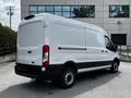 A white 2022 Ford Transit van viewed from the rear and side showcasing its sleek design and cargo space with a black lower section