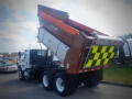 A 2016 International WorkStar 7500 dump truck with a raised cargo bed and a safety display of black and yellow checkerboard patterns on the rear