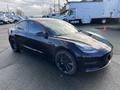 A 2019 Tesla Model 3 in black with tinted windows and black alloy wheels, showcasing a sleek and modern design