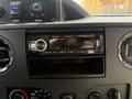 Dashboard of a 2010 Ford Econoline featuring a car stereo with a digital display and various controls for heat and air settings