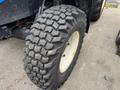 A close-up view of a rugged tire from a 2016 New Holland T475 showcasing its deep tread pattern and white rim