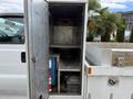 A 2015 Ford F-350 SD with an open storage compartment revealing metal shelves and equipment inside