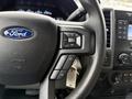 Close-up of the steering wheel of a 2021 Ford F-550 showing controls for volume and media with the Ford logo visible