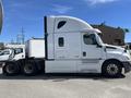 A white 2022 Freightliner Cascadia semi-truck is shown from the side with a tall cab and dual rear axles