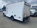 A white 2004 Ford Econoline truck with a boxy cargo area and a side window