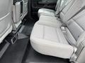 The interior back seat area of a 2015 GMC Sierra 1500 with light gray fabric upholstery and seat belts visible