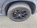 A close-up of a black wheel and tire of a 2009 BMW X5 showing the BMW logo on the center cap and the tire tread pattern