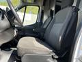 A driver's seat and steering wheel inside a 2022 Ford Transit with gray fabric upholstery and a simple dashboard design