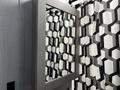 A rectangular mirror with a wooden frame reflecting a geometric patterned curtain in black and white