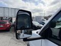 A 2020 Chevrolet Express with a side mirror reflecting surrounding vehicles and a cloudy sky