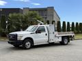 2015 Ford F-350 SD truck with a flatbed and utility box on the side parked on a driveway