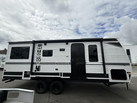 A 2022 Keystone Hideout RDWE 20RDWE travel trailer with a white exterior and black accents featuring multiple windows and a side entry door