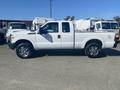 A white 2014 Ford F-250 Super Duty truck with a crew cab and chrome wheels parked in a lot