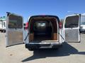 A 2012 Chevrolet Express van with open rear doors revealing a spacious and empty cargo area with wooden flooring and side panels