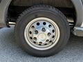 A close-up of a wheel from a 2023 Ford Transit showing a silver rim with multiple circular openings and a black tire with visible tread patterns