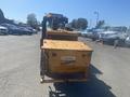 A yellow 2010 Trackless MT6 machine with a large front container and visible branding is positioned prominently in the foreground