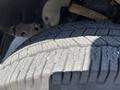 Close-up of a tire from a 2014 Ford F-150 showcasing tread patterns with visible wear and some debris embedded in the grooves
